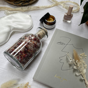 Items that feature in the Bridal large gift box including a grey notebook with Hey You in gold written. Bath salts, organic silk white sleep mask, a nude nail varnish & bio-retinol gold face mask. Silk sari yarn, dried flowers surround the items.