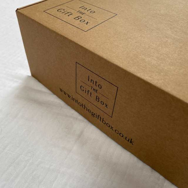 Photo of the corner of a cardboard gift box taken on an angle.  The top has a square logo printed in back with the words Into The Gift Box appearing in the centre. The front side has the same logo with www.intothegiftbox.co.uk beneath.